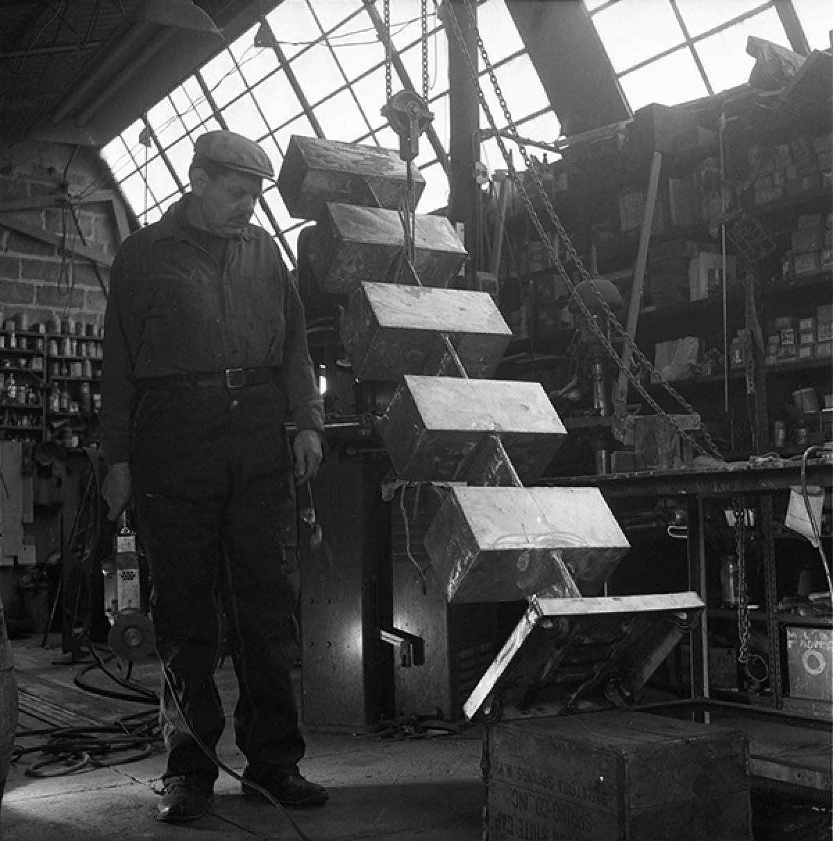 David Smith overseeing the placement of <em>Five Units Equal </em>(1956) onto a base in his workshop at Bolton Landing, 1956